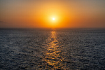 Naklejka premium Golden sunset over the Mediterranean Sea with glowing reflection on calm water
