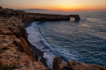 Arch of Skaleta rock formation at sunset on Crete coastline Greece