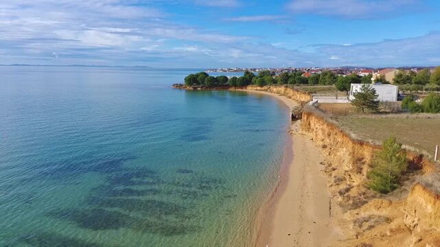 Aerial footage of sand beach near Zaton, Croatia, eroded limestone cliffs and blue adriatic sea.