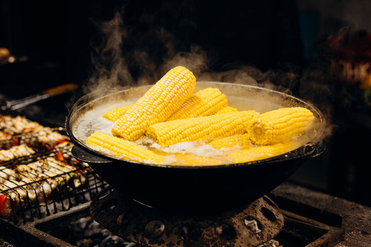 Fresh corn boiling in a street food market setting