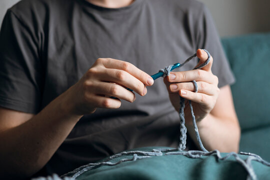 Hands crocheting with a blue hook