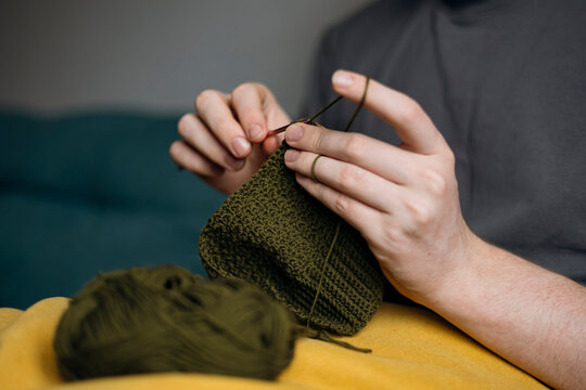 Man knitting with olive green yarn