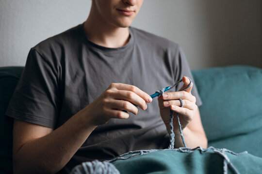 Man relaxing while practicing crochet at home