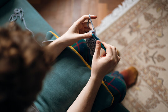 Crocheting with focus on hands and yarn on sofa