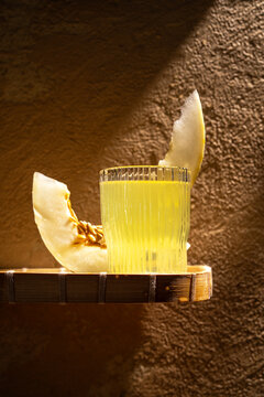 Refreshing melon juice with ripe slice on wooden surface