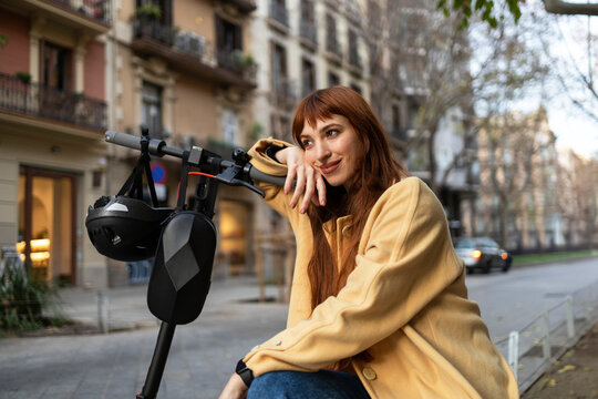 Woman relaxing with electric scooter in urban setting
