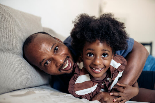 Father and daughter sharing a joyful moment on sofa