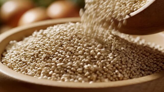 Close-up of quinoa seeds pouring from a wooden scoop into a bowl, healthy food concept