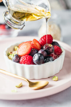 Pouring Agave or Maple Syrup over a Red Berry Yogurt Bowl