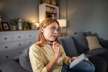 Fototapeta premium Woman thinking journaling on sofa at home