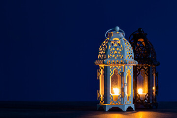 Two ornate Ramadan lanterns with warm candlelight on deep blue background, symbolizing companionship, guidance and hope during peaceful holy nights   © Ricky