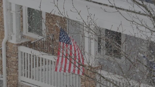 American Flag During Winter Storm Gianna. Strong Snow Blizzard in Winter, Greenville, South Carolina. Blizzard Strong Wind And Heavy Snow Lash Town. American Flag Heavy Snowstorm in Residential Area.