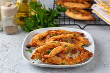 Fototapeta premium Dishes from traditional Turkish cuisine; Mini pita with cheese and minced meat - Turkish name; Kiymali peynirli mini pide