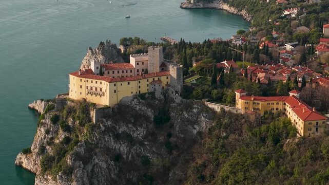 Duino Castle Aerial Side Flight: Close-up of Medieval Fortress Tower Revealing Dramatic Sea Cliffs and Small Beach with Waves, Adriatic Coast, Cinematic Mediterranean Aesthetics Drone 4K