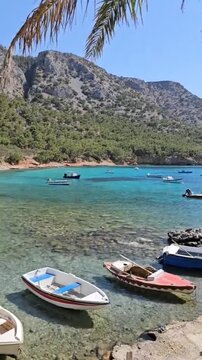 Cinematic 4K Vertical view of crystal clear turquoise sea water through trees in Samos Island Greece