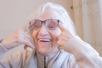 Elderly woman playing with finger gestures and closing her eyes