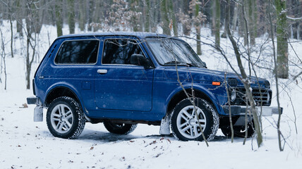 Blue off-road vehicle parked in a snowy forest during winter season