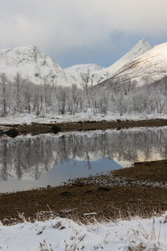 Magical fjord scene with winter wonderland an snow covered mountain peaks on the North Norwegian Island of Senja.