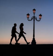 silhouette of runners at the seaside next to a vintage lantern