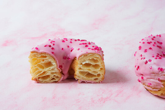 Pink raspberry cronut with strawberry fondant icing cut in half 