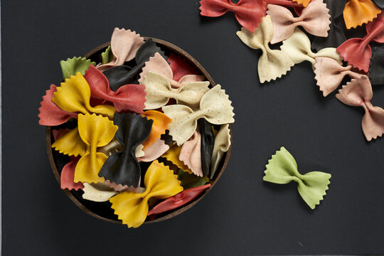 Colorful pasta in a coconut bowl on black background - top view