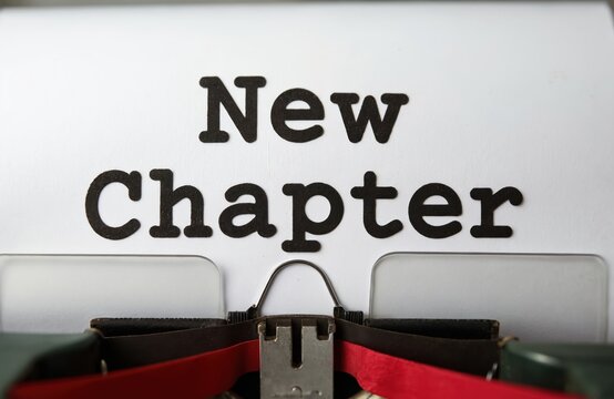 New chapter text typed on old typewriter. Retro writing concept for fresh start idea or next phase. Represents beginning, change, story, or message.