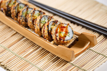 Crispy fried sushi roll with avocado and eel sauce Japanese crunchy sushi roll served on a bamboo tray Tempura sushi roll with avocado and cucumber filling © Mykhailo Feriukov