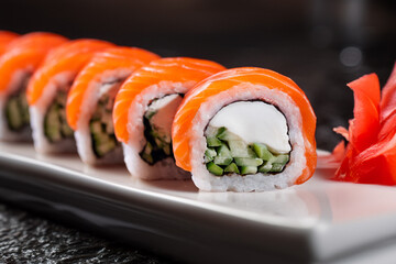 Salmon sushi roll with cream cheese and cucumber filling Philadelphia style sushi roll topped with fresh salmon Fresh salmon roll served in modern restaurant style © Mykhailo Feriukov