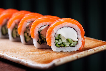Salmon sushi roll with cream cheese and cucumber filling Philadelphia style sushi roll topped with fresh salmon Fresh salmon roll served in modern restaurant style © Mykhailo Feriukov