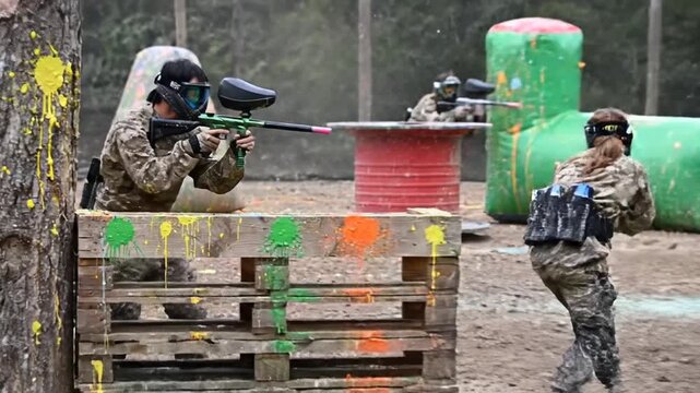 Man and woman playing paintball in outdoor arena