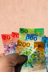 Man hand holding Swiss Franc money banknotes, showing paper texture and symbols of Swiss currency