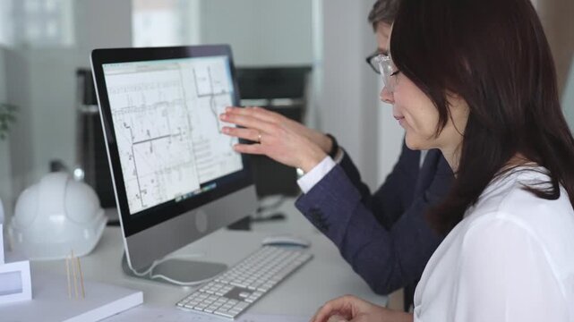 Architects collaborating on building plans using computer aided design software and architectural models. Business and architecture concept