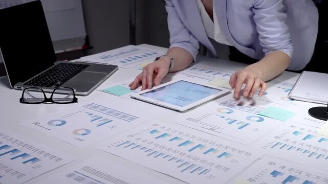 Person analyzing financial data, reviewing business analytics reports, using a laptop with charts, and planning corporate strategy with spreadsheets and investment figures