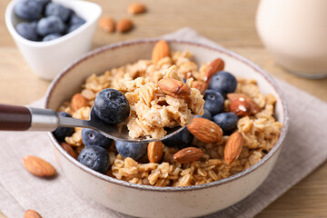 Oat flakes with almonds, blueberries and milk on wooden table, closeup