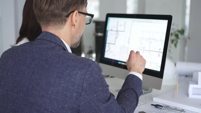 Architecture and engineering team collaborating on project blueprints using computer aided design software in an office. Business and architecture concept
