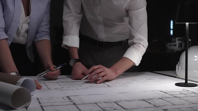 Architects and engineers collaborating on blueprint plans, working together on an architecture project layout design late at night.
