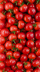 Full frame background of glossy cherry tomatoes forming a dense red food texture. Ideal for culinary design, food advertising and healthy eating concepts.
