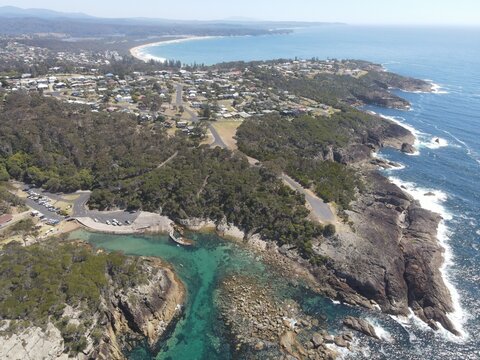 A high, drone view of Kianinny Bay in Tathra, NSW, Australia. Sapphire Coast, clear water, boat ramp, fishing, fishing club, summer, swimming, rocks.