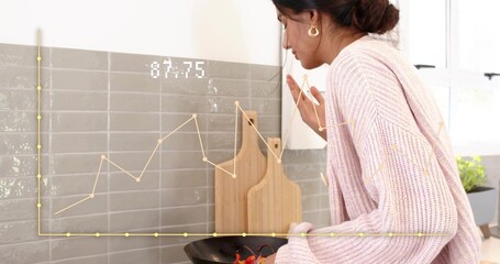 Leaning Indian woman pink-knit checking pan in kitchen red-veg backsplash 87