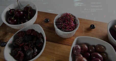 Naklejka premium Showing wooden cutting board holding white ceramic bowls on studio tabletop, with cherries, olives