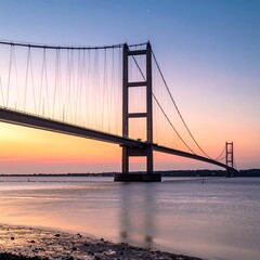 Obraz premium Long suspension bridge over calm water at dusk with colorful sky reflecting