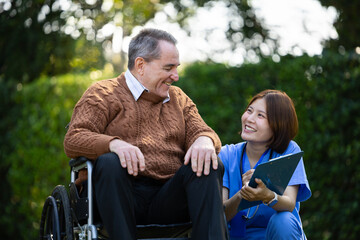 Friendly caregiver and senior man in a wheelchair sharing a joyful conversation outdoors, representing compassion and elderly support.