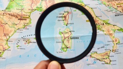 View of Sardinia Island, Corsica Island, on a geographical map of Europe, seen using a magnifying glass © PinkyEn