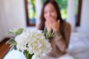 Blurred image of a surprised woman receiving a white flower bouquet at home