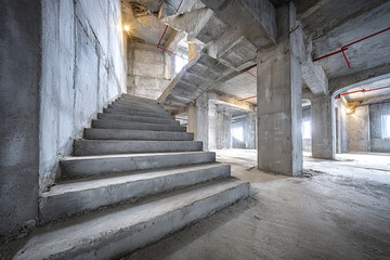 Fototapeta premium Industrial unfinished interior with multi level concrete staircases and exposed columns in spacious building under construction with natural light