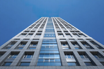 Obraz premium Modern high rise building with glass facade and concrete structure under clear blue sky, showcasing minimal architectural design and urban environment with reflective windows