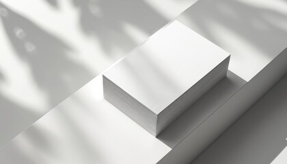 Stack of blank white business cards on a clean surface. Leaf shadows create natural light patterns. Use for branding mockups or graphic design.