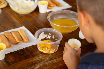 Kids making tiramisu dessert at cooking workshop, hands preparing ingredients on wooden table, family culinary class and learning concept