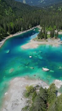 Lake Cauma turquoise water Switzerland aerial drone vertical video surrounded by evergreen forest