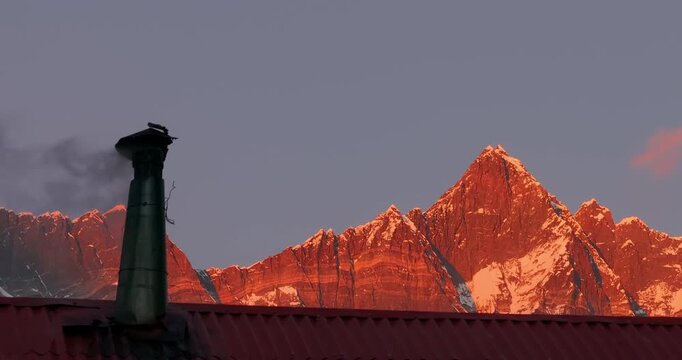 Revealing snowless Himalayan mountains at sunset golden hour in Nepal&rsquo;s Everest region. Smoke rising from village chimneys reflects local lifestyle amid visible environmental change and high-altitude
